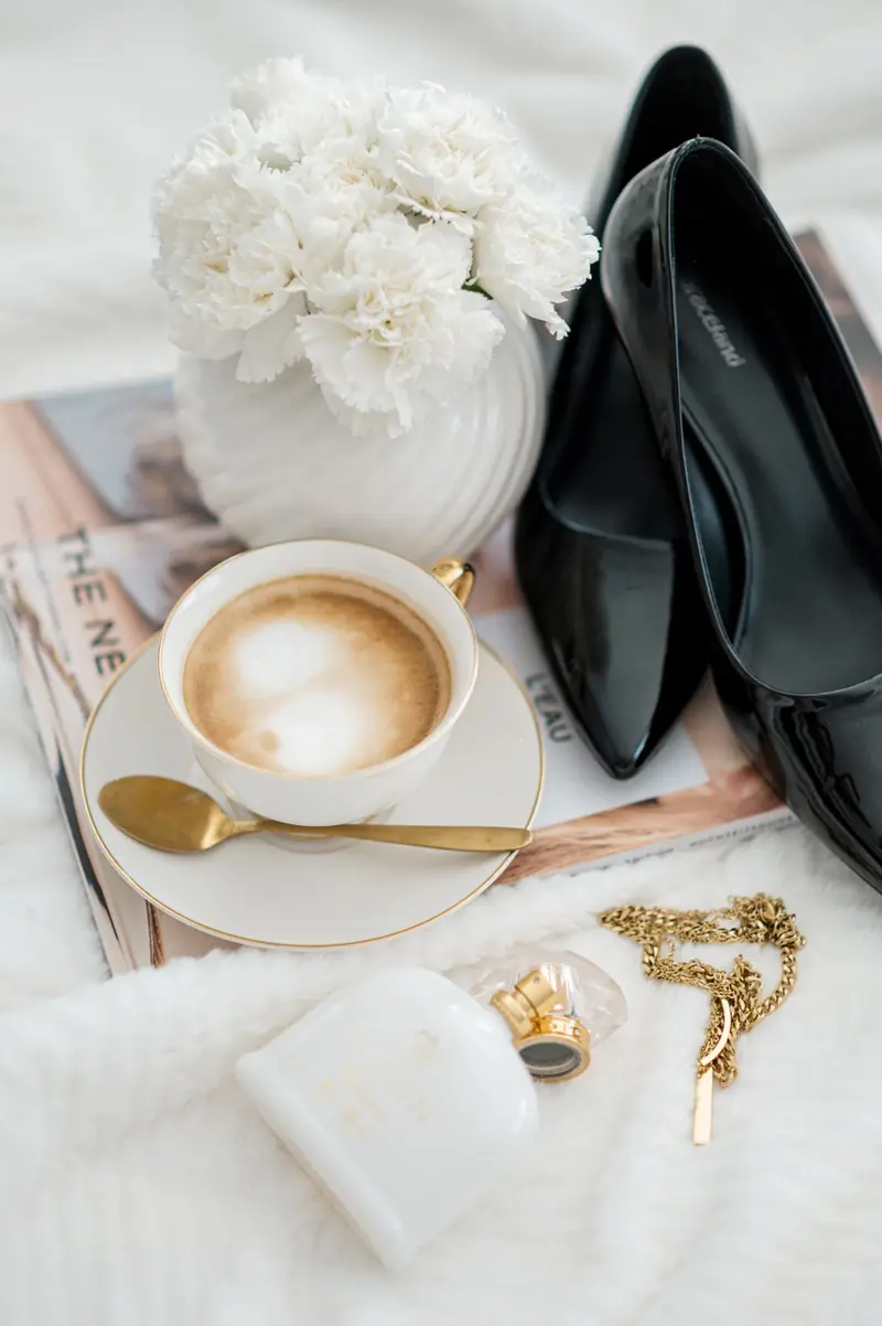 Elegante Schuhe, Magazin und Kaffee auf hellem Stoff